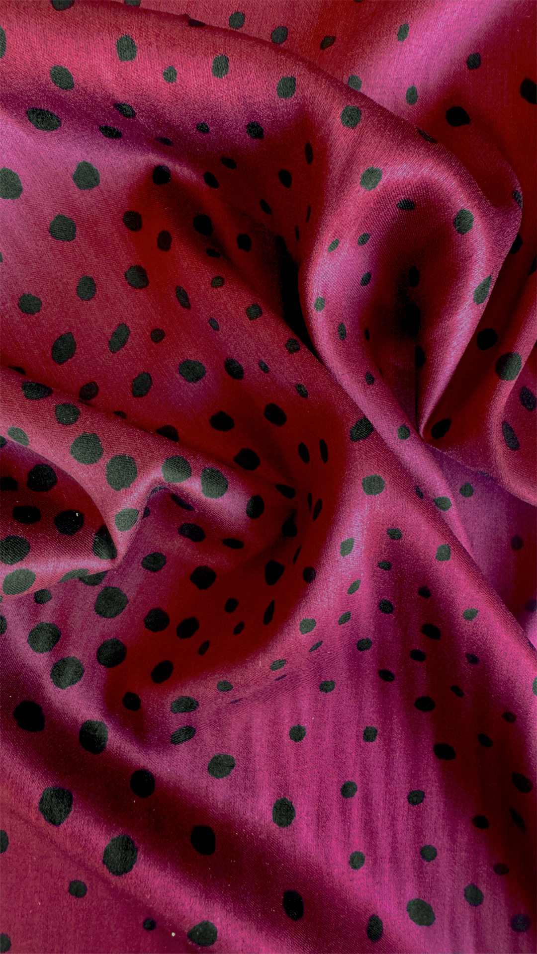 Tessuto in viscosa con micro-pois neri che sfumano su un fondo magenta